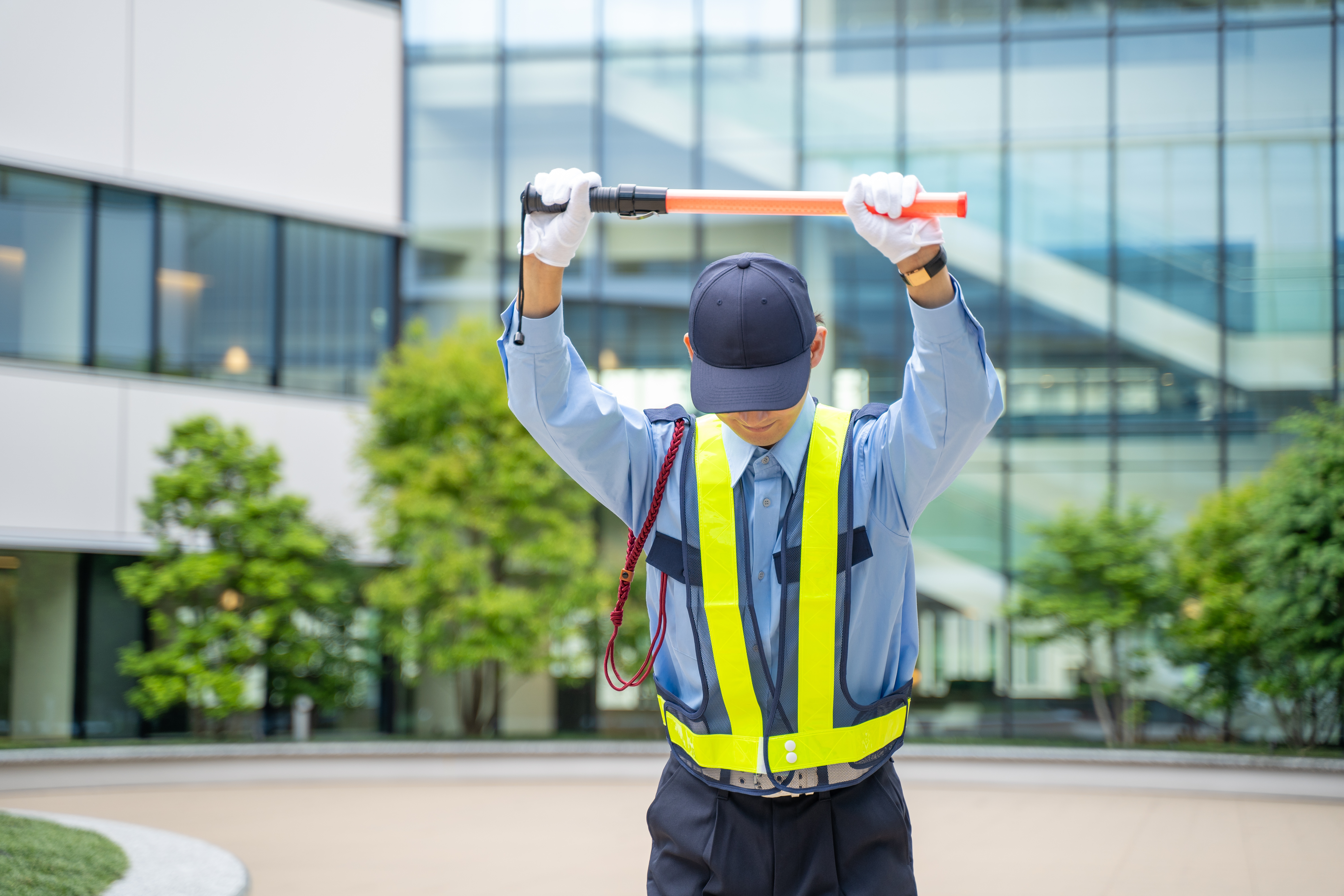 誘導棒を持ってお辞儀をするガードマン男性